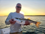 Angler with scenic Lake Texoma backdrop and fresh striper, Stripers Inc.